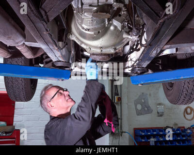 Classic car mechanics working on a car in their workshop Stock Photo