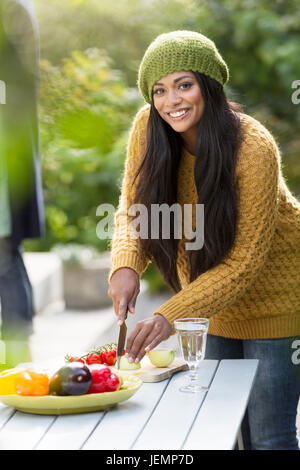 Smiling young woman cutting vegetables Stock Photo