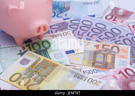 Pink piggy bank surrounded by euro banknotes Stock Photo