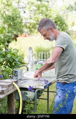 Man washing dishes in garden Stock Photo