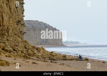 West Bay, Dorset, UK. 27th June, 2017. A fisherman packs away his rods beside a new rock fall on West Bay's iconic cliffs. The sizeable fall was thought to have happened on Sunday afternoon. A Coastguard post on Facebook stated 'Whenever the team is out on patrol, we always check East Beach and give safety advice to those who have set themselves up for the day under the cliffs. **THIS IS WHY**' Credit: Tom Corban/Alamy Live News Stock Photo