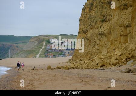 West Bay, Dorset, UK. 27th June, 2017. Walkers skirt the shore to put as much distance as possible between themselves and a new rockfall on West Bay's iconic cliffs. The sizeable fall was thought to have happened on Sunday afternoon. A Coastguard post on Facebook stated 'Whenever the team is out on patrol, we always check East Beach and give safety advice to those who have set themselves up for the day under the cliffs. **THIS IS WHY**' Credit: Tom Corban/Alamy Live News Stock Photo
