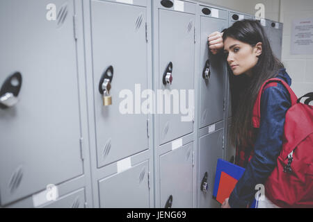 Sad student leaning on locker Stock Photo