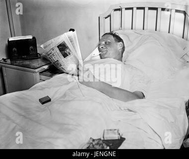 Man Smoking Cigarette while Reading Newspaper in Hospital Bed, Harris & Ewing, 1936 Stock Photo