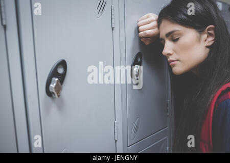 Sad student leaning on locker Stock Photo