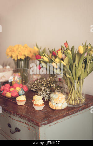 Bright macaroons and cupcakes on a wooden table. Indoors natural light shot with small depth of field Stock Photo