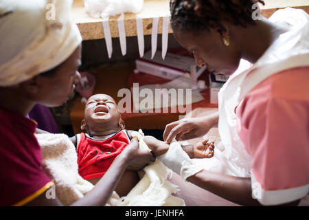 A nurse administers medication to a child intravenously at a hospital in Bundibugyo, Uganda. Stock Photo