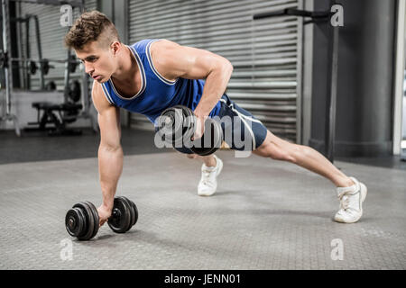 Muscular man doing push up with dumbbells Stock Photo