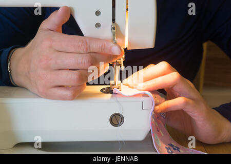 A young woman using a sewing machine Stock Photo