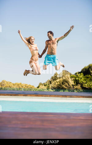 Happy couple jumping in the pool Stock Photo
