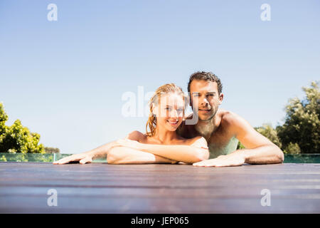 Happy couple leaning on pool edge Stock Photo