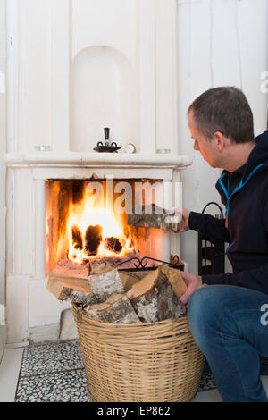 Man putting wood in fireplace Stock Photo