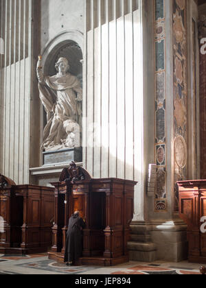 A priest by a confessional inside St. Peter's Basilica Stock Photo