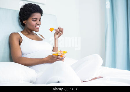 Pregnant woman eating fruit salad Stock Photo