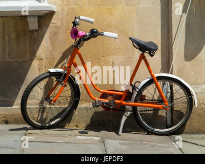 A kid's orange bike parked outside a houe Stock Photo