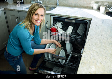 Pretty blonde woman emptying the dishwasher Stock Photo