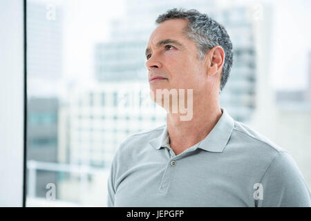 Tensed man standing against window Stock Photo