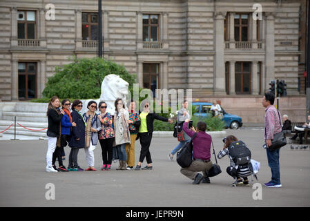 Asian tourists in George Square Glasgow Scotland taking selfies and photographs mainly Chinese and Japanese people Stock Photo
