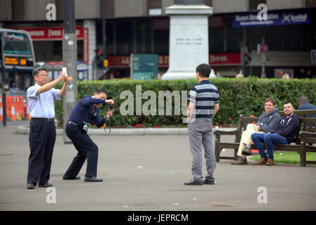 Asian tourists in George Square Glasgow Scotland taking selfies and photographs mainly Chinese and Japanese people