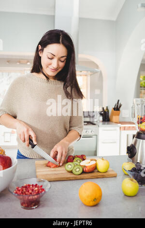 Happy woman cutting fruits Stock Photo