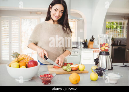 Portrait of happy woman cutting fruits Stock Photo