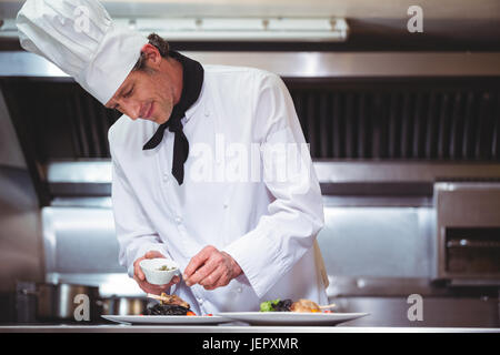 Chef sprinkling spices on dish Stock Photo