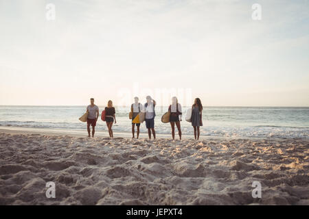 Happy friends walking with surfboards
