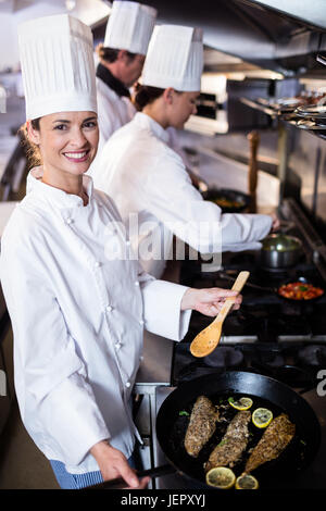 Chef frying fish in a frying pan Stock Photo