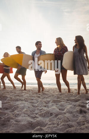 Happy friends walking with surfboards