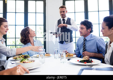 Waiter serving water to business people Stock Photo