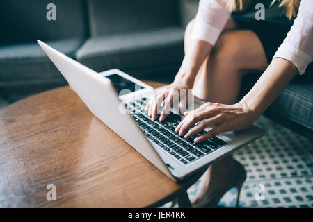 Close-up picture of female hands typing on laptop placed on desk