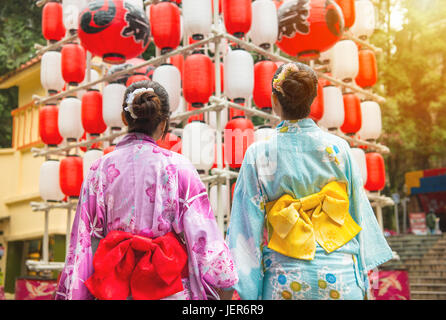 Back view of girlfriends looking up at lantern in Japanese festival. Japanese women wearing japan traditional kimono enjoying view of art decoration d Stock Photo