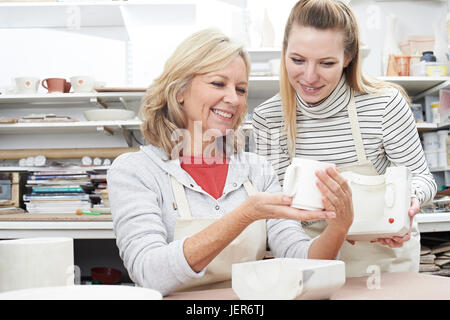 Teacher With Mature Woman Making Mug In Pottery Class Stock Photo