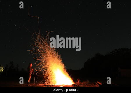 Blurry person, clear flame. Wild sparks fly freely through the dark air. The heat is yet in front of us, but the best is yet to come. Stock Photo