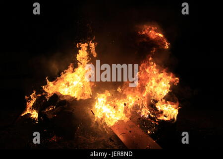 Dark pieces of wood burning in orange-yellow flame in the fire full of  ashes Stock Photo - Alamy