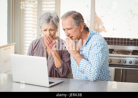 Shocked senior couple looking at laptop Stock Photo