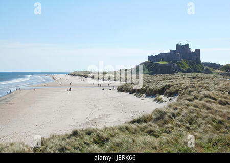 Bamburgh castleon its rock looking along sand dunes and sea coast Stock Photo