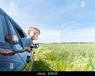 Smiling boy in car near wind turbines Stock Photo