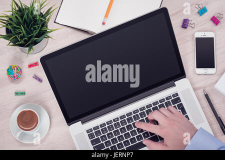Workplace with laptop on the office desk with mans hand on keyboard top view Stock Photo