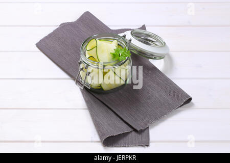 jar of raw zucchini strips on grey place mat Stock Photo