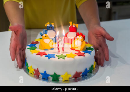 A colourful birthday cake with two lit candles Stock Photo - Alamy