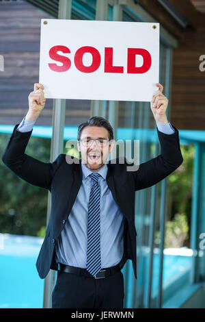 Real estate agent holding sold sign Stock Photo