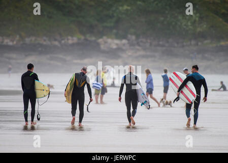 Surfing UK. Four surfers carrying their surfboards walking across Fistral beach in Newquay, Cornwall. Stock Photo