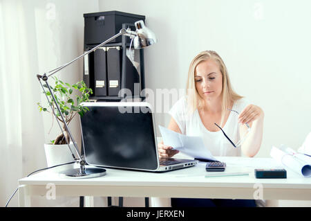 Blonde architect is reading documents at her office Stock Photo