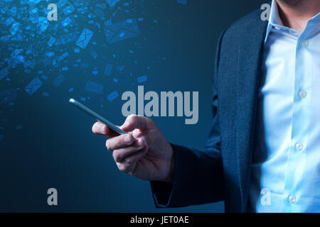 Businessman sending bulk messages using smartphone, male business person in elegant suit delivering e-mails, newsletters or SMS text messages with his Stock Photo