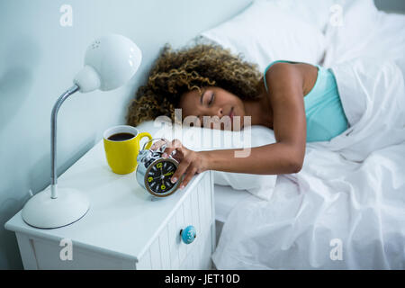 Woman stopping alarm while sleeping on bed Stock Photo