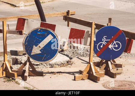 Road works and weather worn traffic signs, detour and bicycles lane ends signage Stock Photo