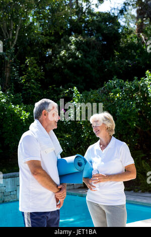Active senior couple talking at poolside Stock Photo