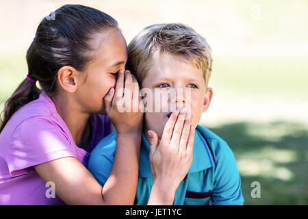 Girl whispering in her brothers ear Stock Photo