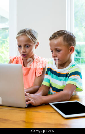 Curious siblings using laptop at home Stock Photo